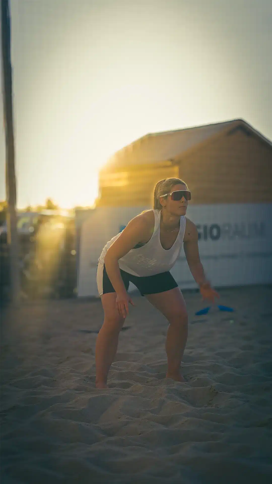 Frau trainiert beim Sonnenuntergang auf dem Beachfeld im Sportraum Mainz, barfuß im Sand