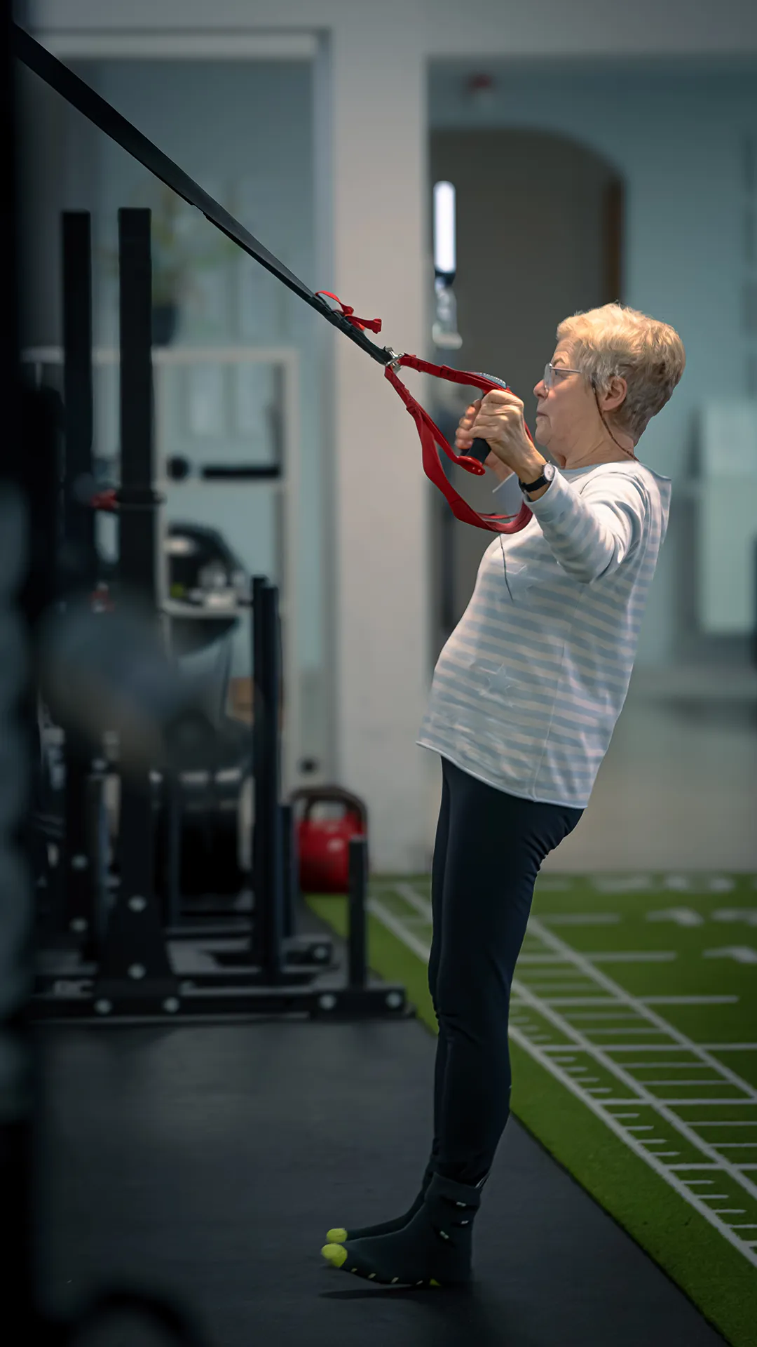 Mitglied macht leichte Übung mit Wandgurten gegen Rückenschmerzen