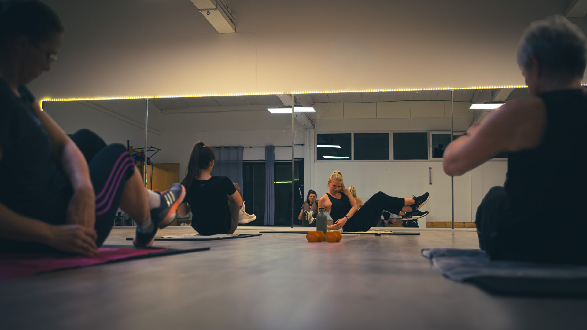 Die Kursgruppe folgt der Übung der Trainerin, bei einer Situp ähnlichen Übung