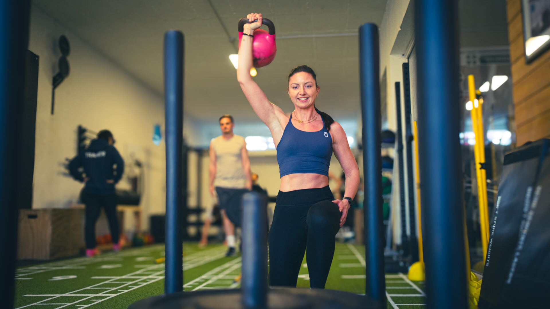 Eine Teilnehmerin hebt ein Gewicht über den Kopf und läuft eine Strecke