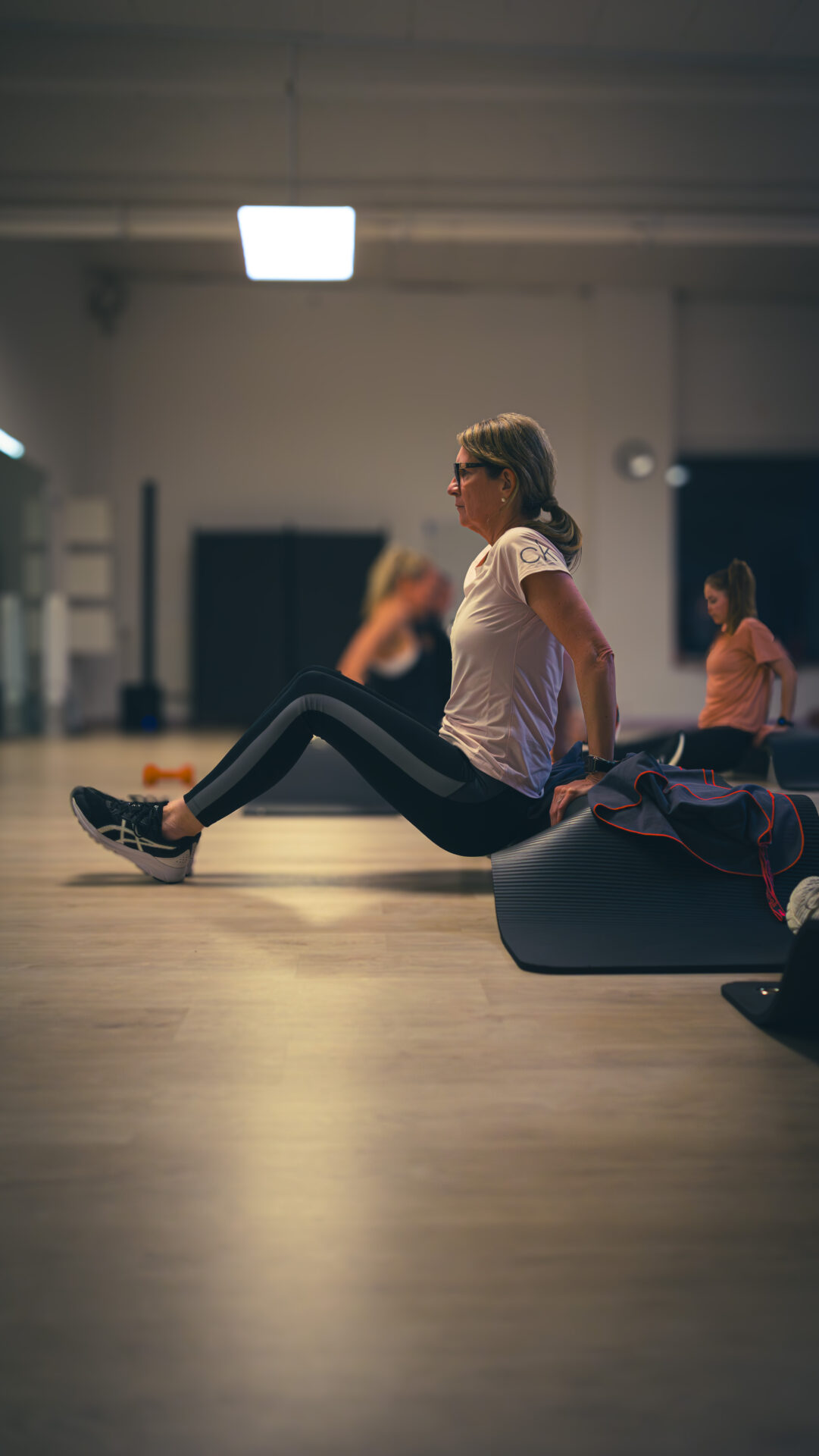 Eine Teilnehmerin macht eine Übung mit abstützen auf dem Stepper und auf den Fersen, sodass der Körper in der Luft ist