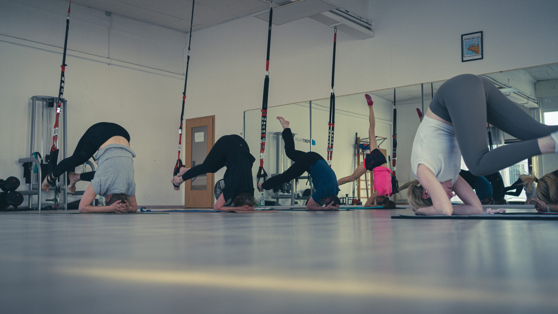 Teilnehmerinnen sind auf dem Kopfstand und stabilisieren sich mit dem Fuß in einer Schlinge