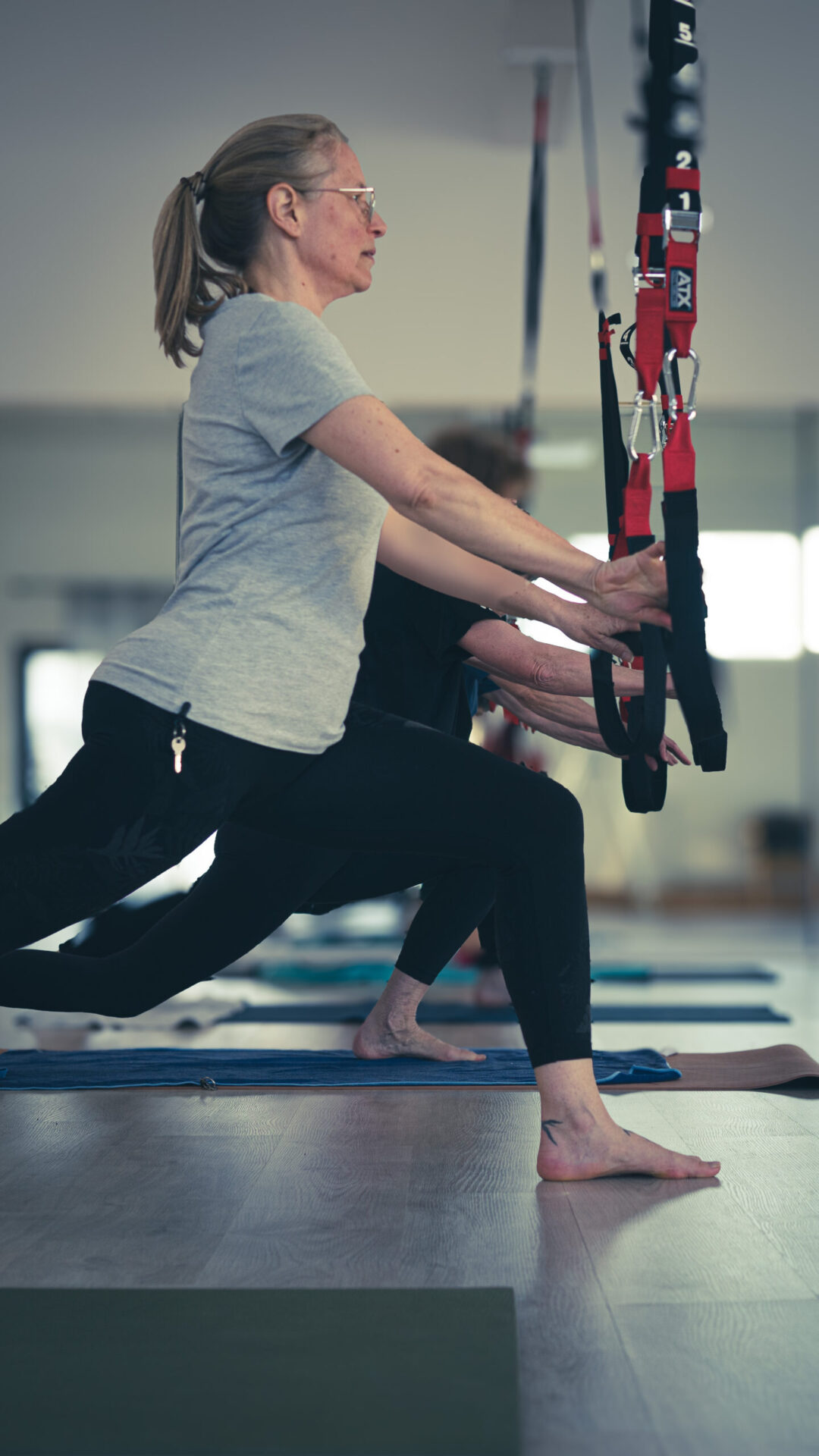 Eine Teilnehmerin des Kurses dehnt ihren Körper und hält dabei die Schlingen fest